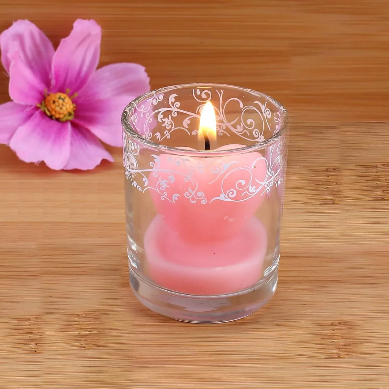Bezaubernde Herzförmige rosa Kerze im Glas