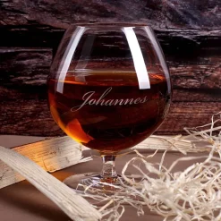 Cognac-Kollektion aus verschiedenen Weinbränden mit Weinbrandglas in gravierter Holzkiste