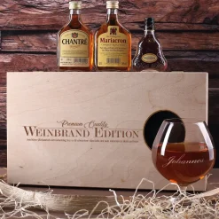 Cognac-Kollektion aus verschiedenen Weinbränden mit Weinbrandglas in gravierter Holzkiste