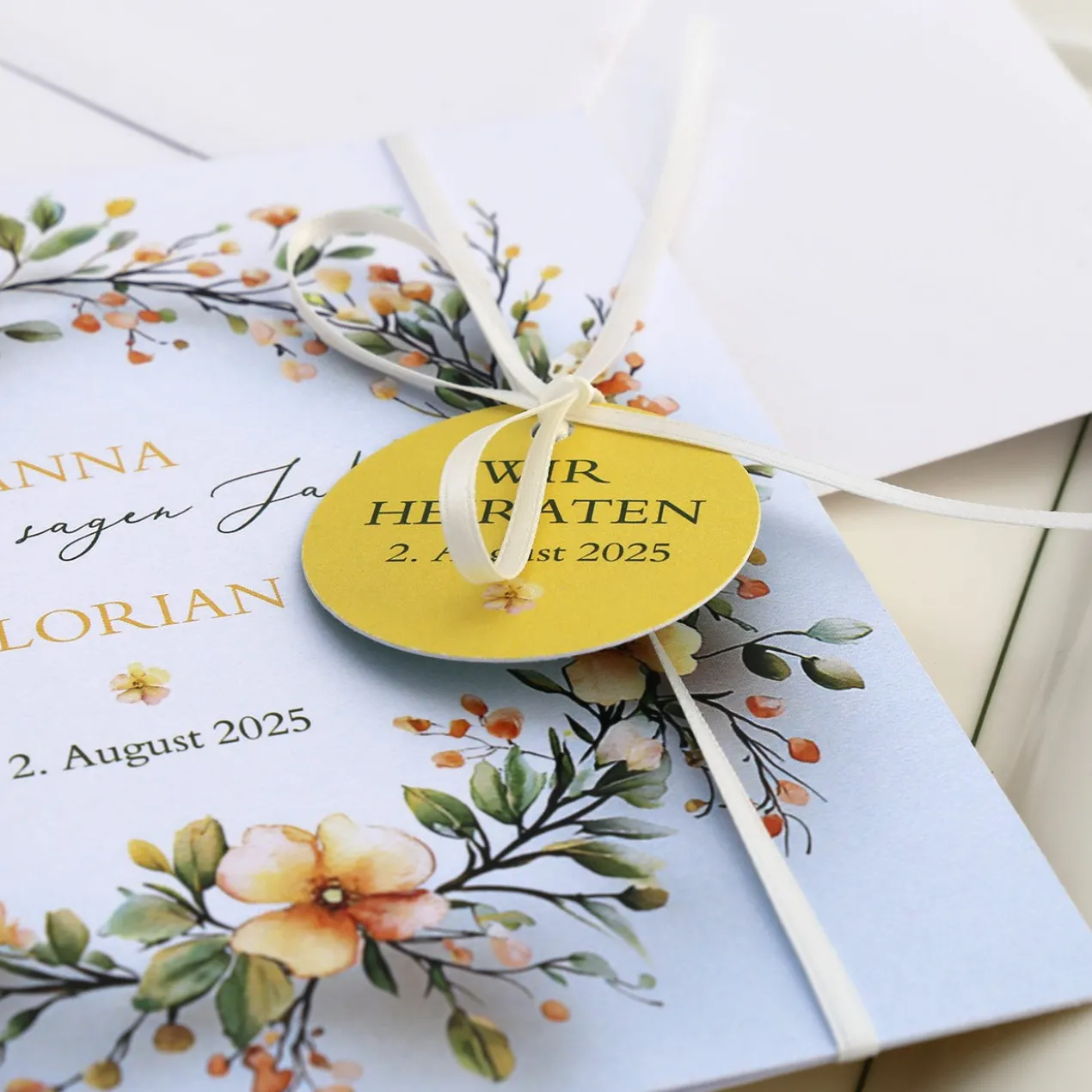 Einladungskarte zur Hochzeit mit Blütenkranz und rundem Anhänger