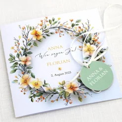 Einladungskarte zur Hochzeit mit Blütenkranz und rundem Anhänger