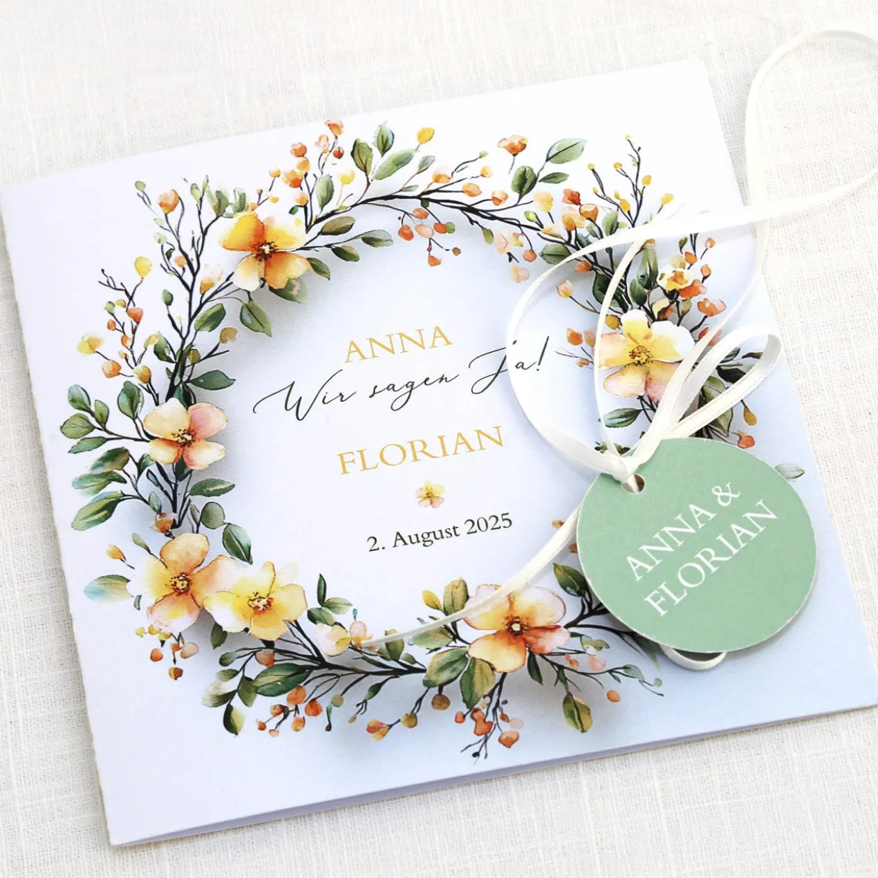 Einladungskarte zur Hochzeit mit Blütenkranz und rundem Anhänger