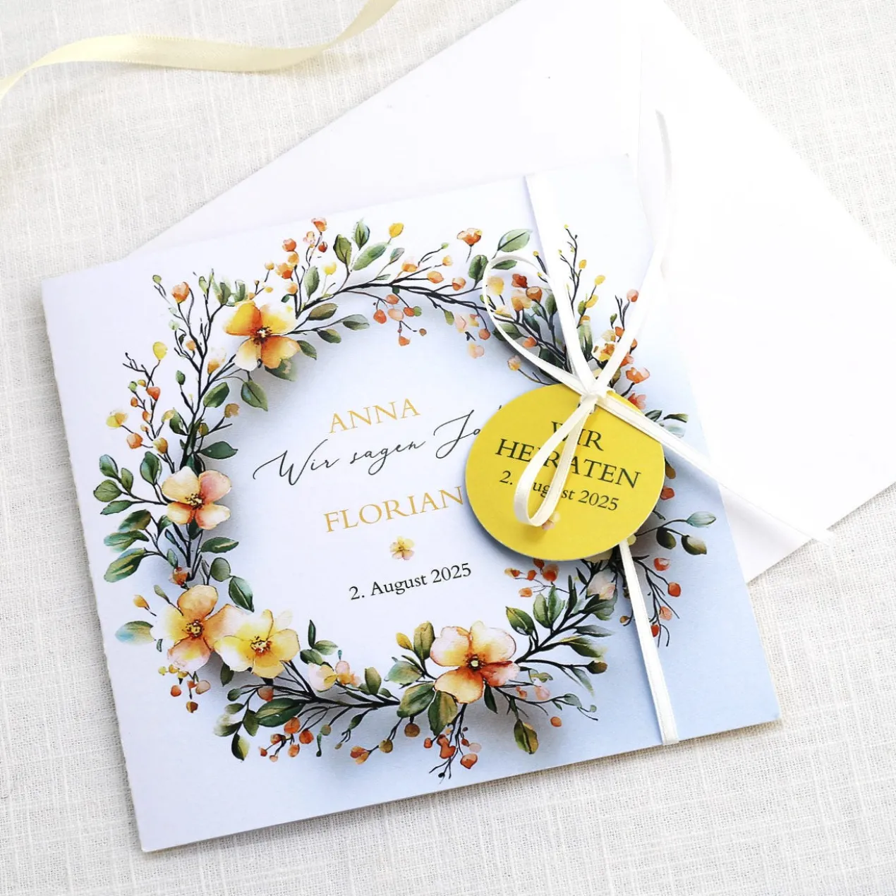 Einladungskarte zur Hochzeit mit Blütenkranz und rundem Anhänger