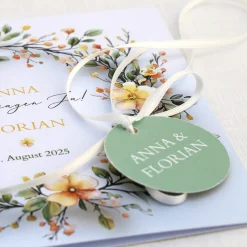 Einladungskarte zur Hochzeit mit Blütenkranz und rundem Anhänger