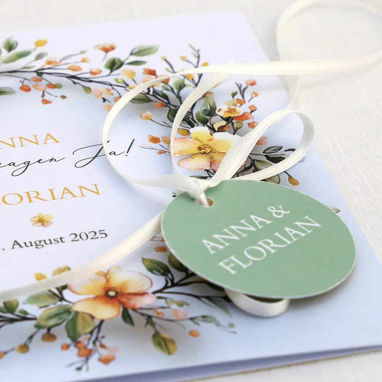 Einladungskarte zur Hochzeit mit Blütenkranz und rundem Anhänger