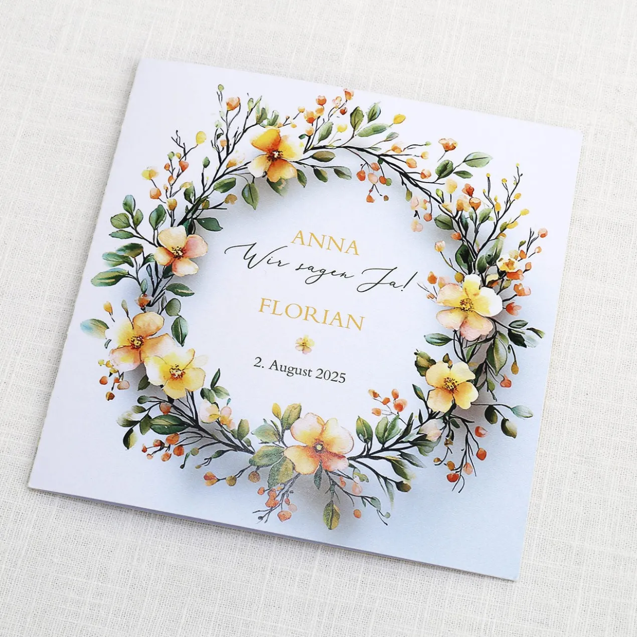 Einladungskarte zur Hochzeit mit Blütenkranz und rundem Anhänger